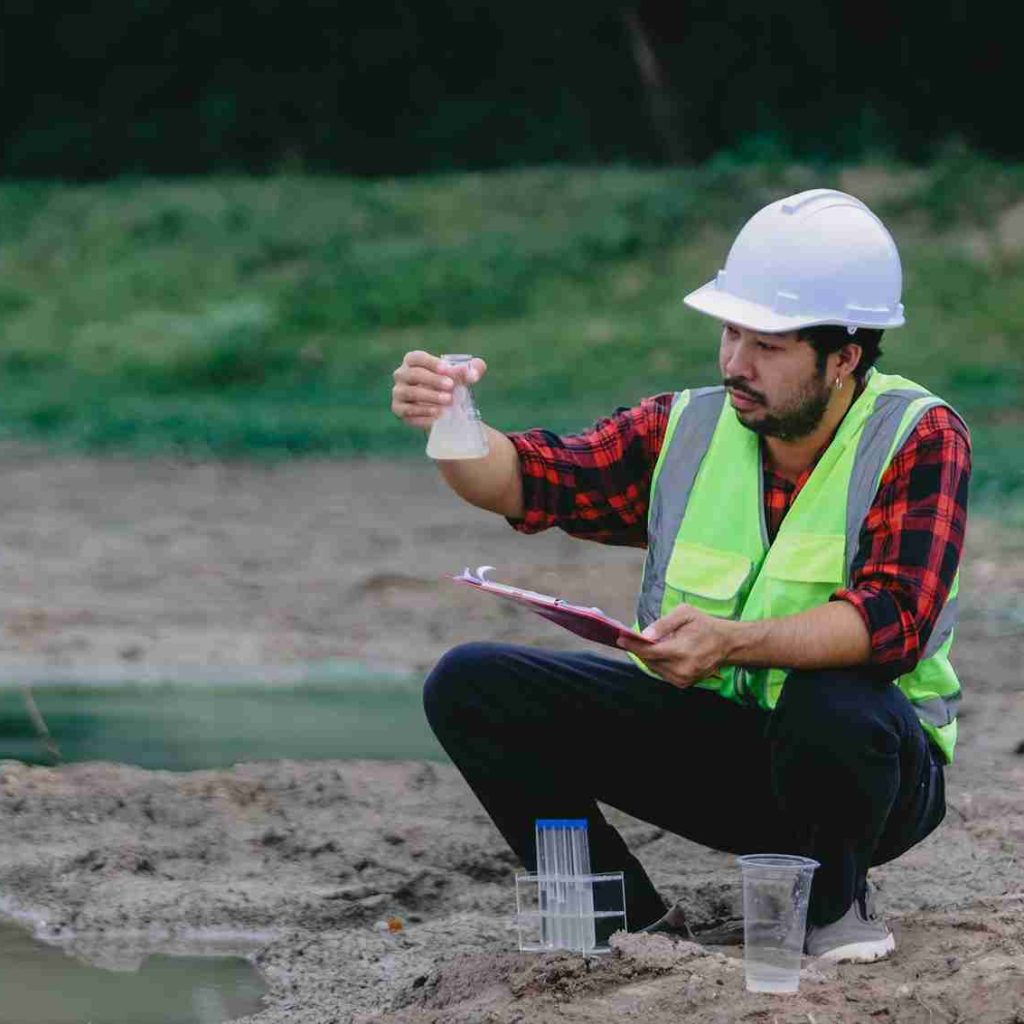 man-red-shirt-green-vest-is-kneeling-down-looking-body-water_11zon